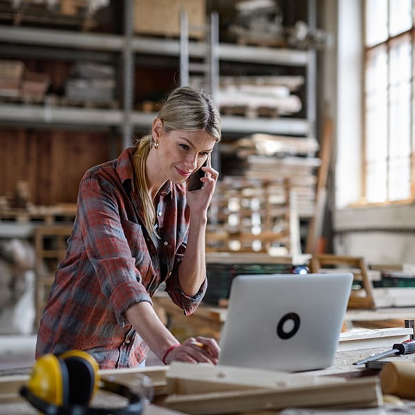 Local business owner on her phone and laptop learning about local seo packages