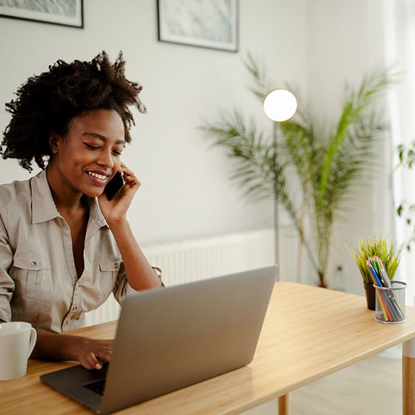 Woman on laptop and phone discussing What to Ask Before You Start a Website Redesign